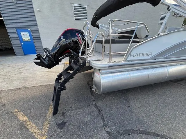 Slide: The Image of 2025 Harris Cruiser 210 pontoon boat with outboard motor, docked on pavement. - 24
