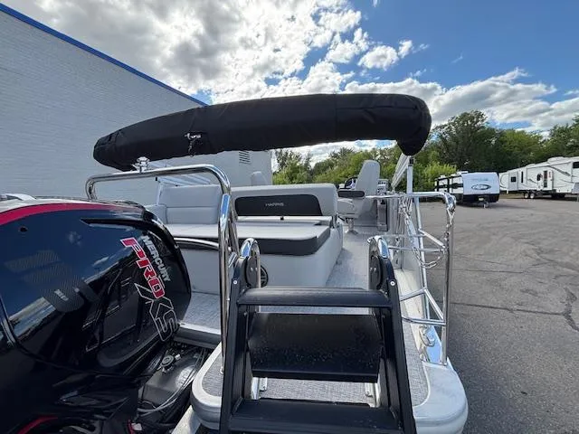 Slide: The Image of 2025 Harris Cruiser 210 pontoon boat with black canopy and powerful engine, parked outdoors. - 25