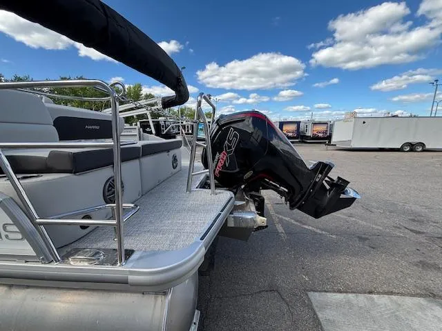 Slide: The Image of 2025 Harris Cruiser 210 pontoon boat with outboard motor, parked under a blue sky. - 28