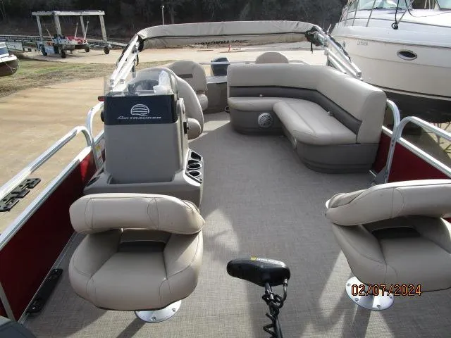 Slide: The Image of 2023 Sun Tracker Bass Buggy pontoon boat interior with beige seating and steering console. - 4