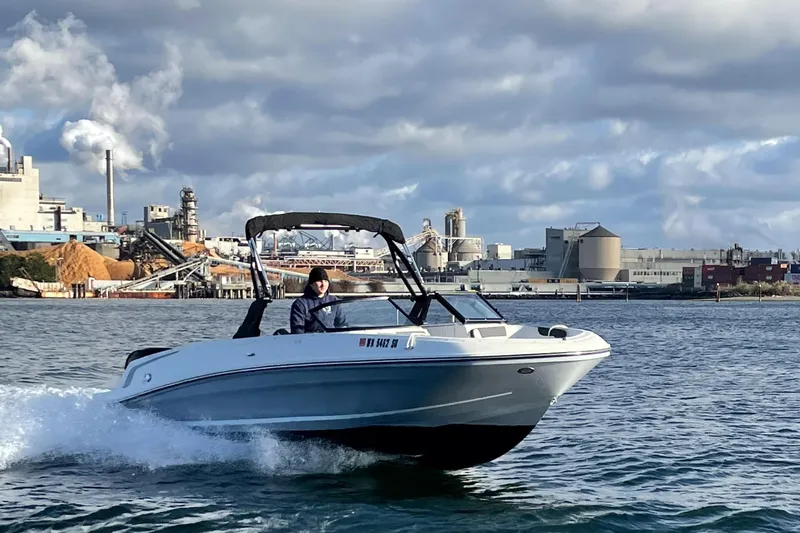 Slide: The Image of 2020 Bayliner VR6 boat cruising on water near industrial backdrop. - 26