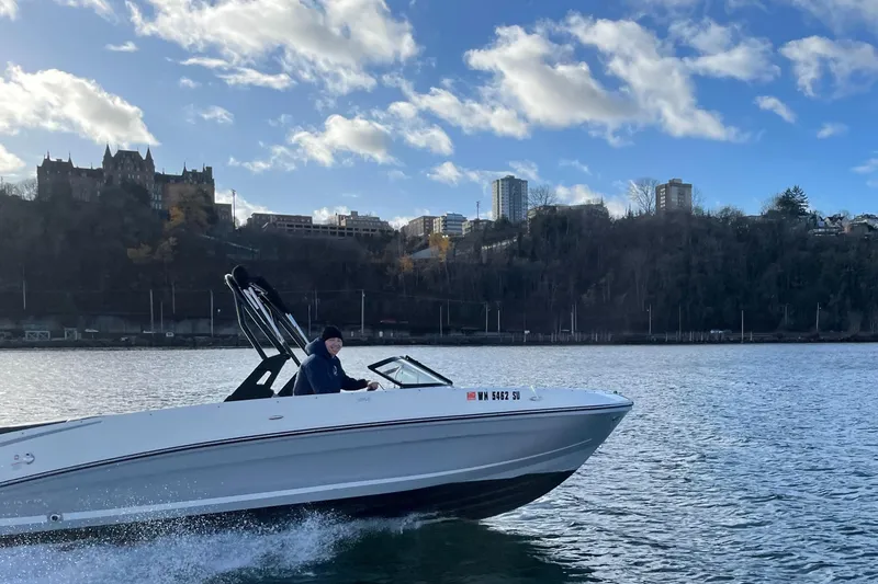 Slide: The Image of 2020 Bayliner VR6 boat cruising on a scenic waterway with city skyline backdrop. - 27