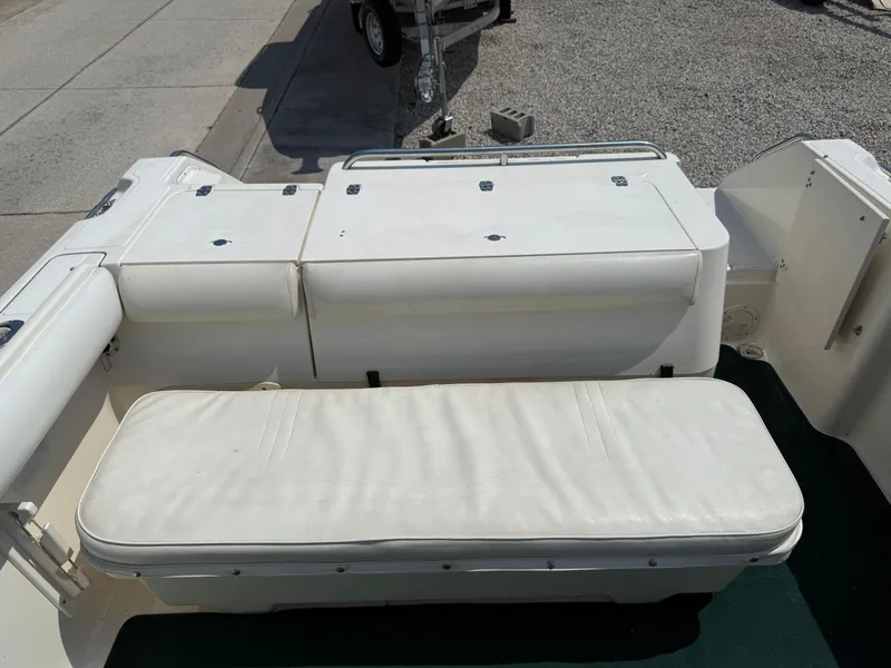Slide: The Image of 1996 Pursuit 2460 Denali boat interior with white cushioned seating. - 10