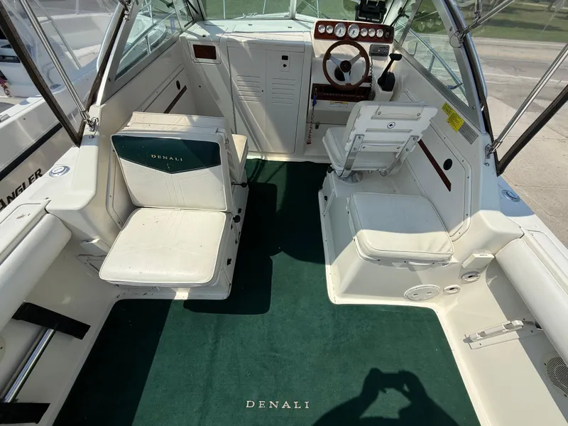 Slide: The Image of 1996 Pursuit 2460 Denali boat interior with green carpet and white seating. - 11