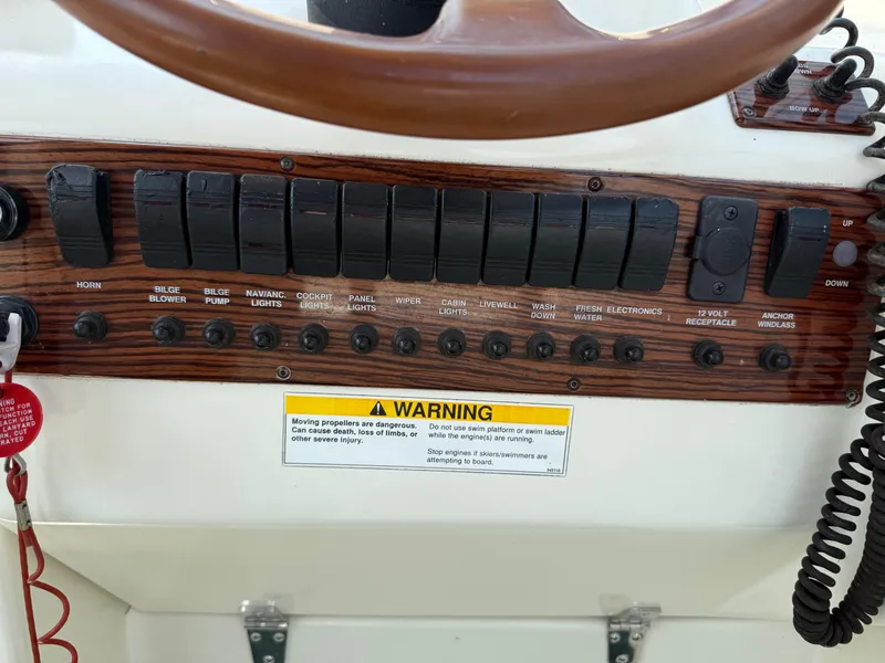 Slide: The Image of 1996 Pursuit 2460 Denali boat control panel with switches and warning label. - 16