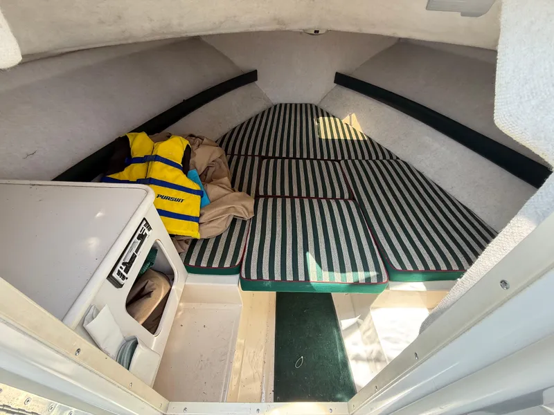 Slide: The Image of Interior cabin of a 1996 Pursuit 2460 Denali boat with striped cushions and a life jacket. - 18