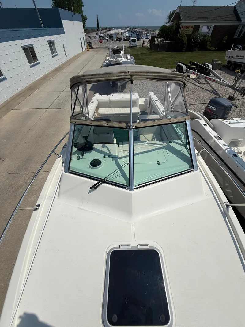 Slide: The Image of 1996 Pursuit 2460 Denali boat docked, featuring a sleek white deck and windshield. - 22