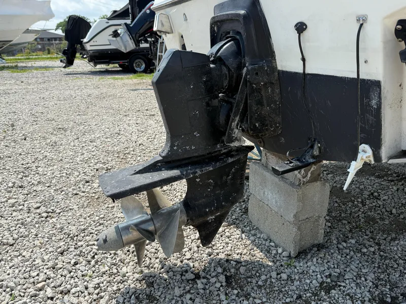 Slide: The Image of 1996 Pursuit 2460 Denali boat propeller and outdrive on gravel surface. - 5