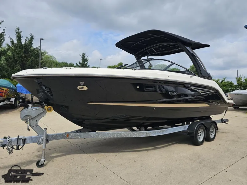 Slide: The Image of 2016 Sea Ray 250 SLX boat on trailer, parked outdoors under cloudy sky. - 16