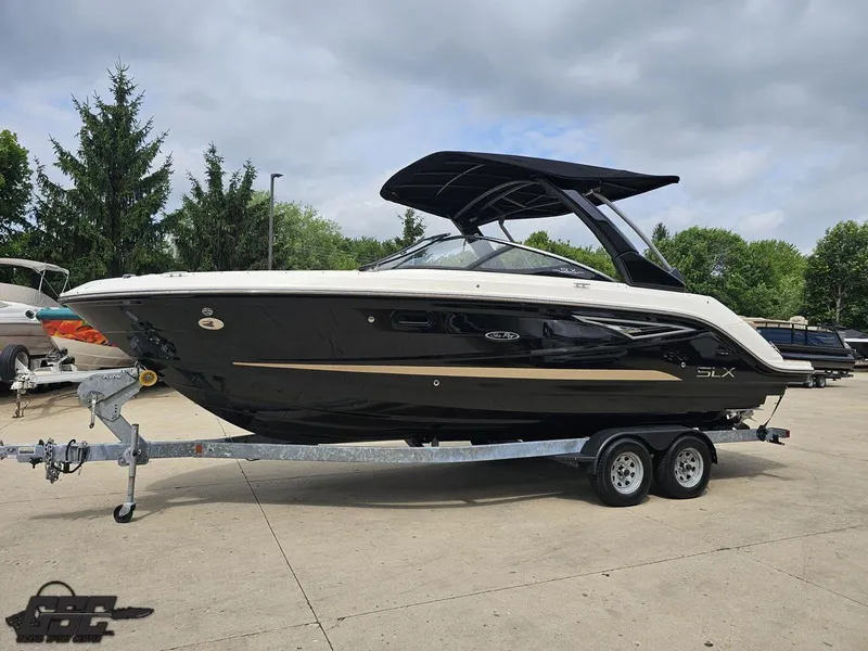Slide: The Image of 2016 Sea Ray 250 SLX boat on trailer, parked outdoors, with trees in the background. - 17