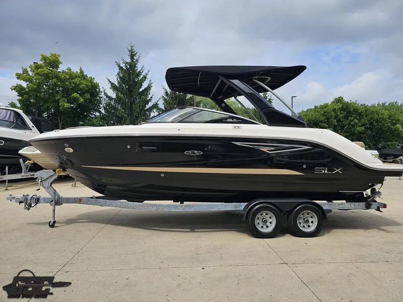Slide: The Image of 2016 Sea Ray 250 SLX boat on trailer, parked outdoors with trees in background. - 18