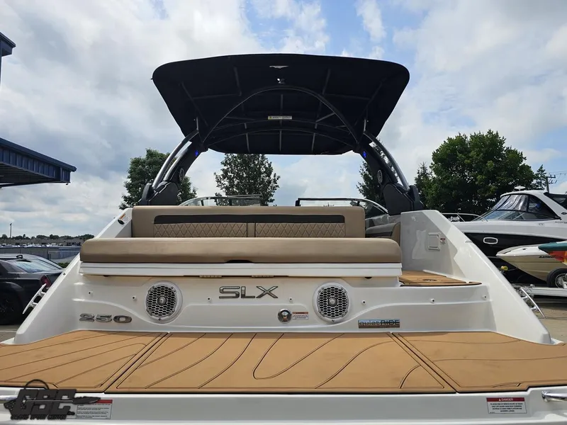 Slide: The Image of 2016 Sea Ray 250 SLX boat with tan seating and black canopy, docked outdoors. - 27