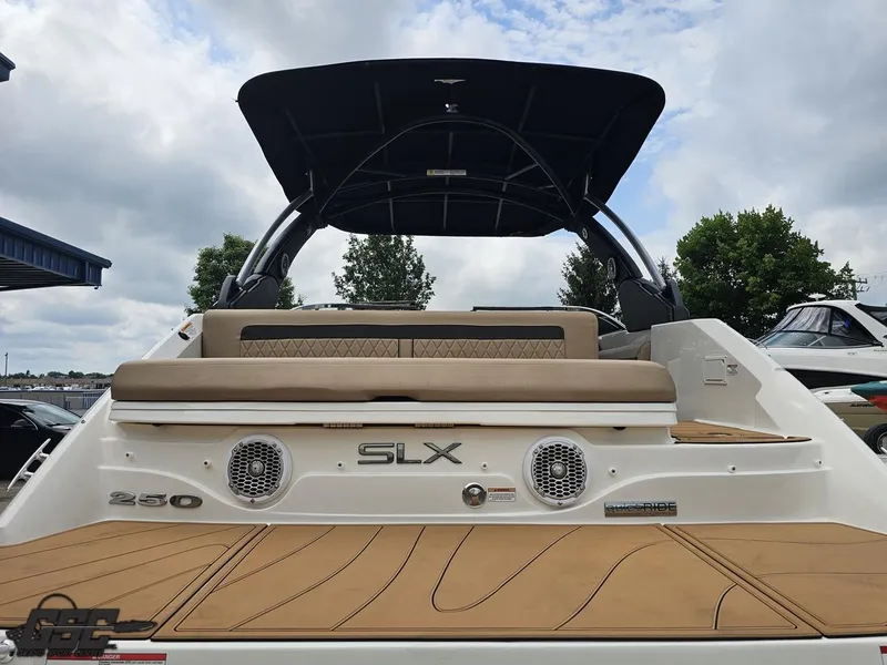 Slide: The Image of 2016 Sea Ray 250 SLX boat with tan seating and black canopy, docked under cloudy sky. - 28