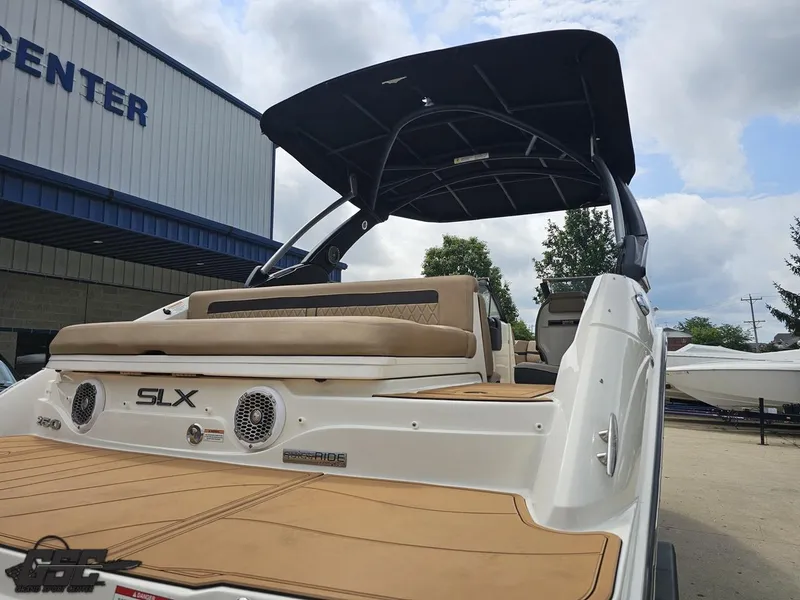 Slide: The Image of 2016 Sea Ray 250 SLX boat with tan seating and black canopy at a marina. - 29