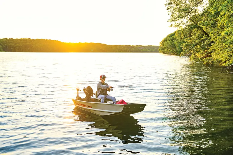 Slide: The Image of Manufacturer Provided Image: 2026 Tracker Grizzly 10 Jon boat on serene lake at sunset, person fishing. - 17