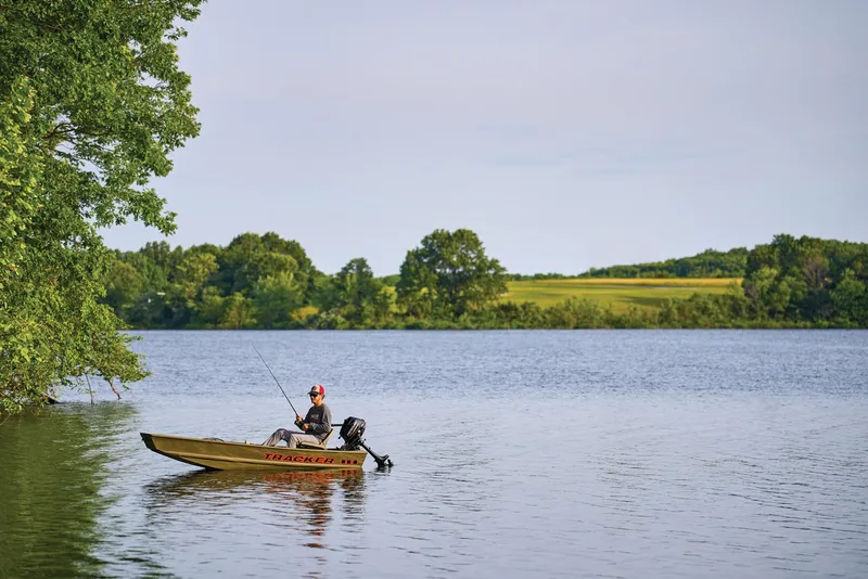 Slide: The Image of Manufacturer Provided Image: Person fishing on a 2026 Tracker Grizzly 10 Jon boat in a serene lake. - 21