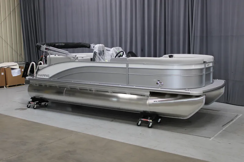 The Image of 2025 Harris Cruiser 210 pontoon boat in a showroom, silver exterior, side view. - 0