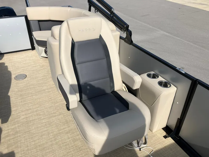 Slide: The Image of 2025 Harris Cruiser 230 boat interior with beige and gray seating, cup holders, and carpeted flooring. - 12