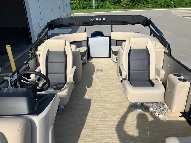 Slide: The Image of 2025 Harris Cruiser 230 interior with beige seating and steering wheel, docked near a warehouse. - 17