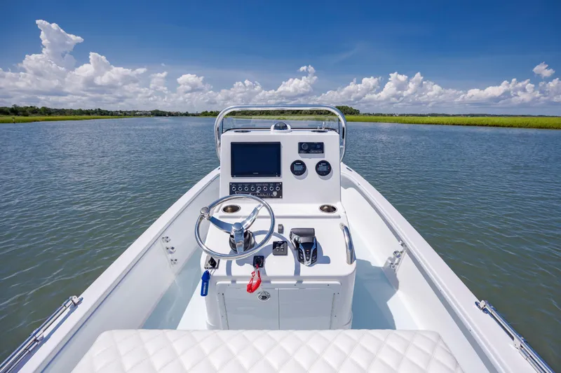 Slide: The Image of 2025 Spanish Wells 21 boat on calm water, featuring modern dashboard and steering wheel. - 12