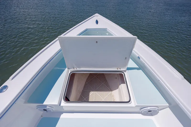 Slide: The Image of Bow of 2025 Spanish Wells 21 boat with open storage compartment on calm water. - 19