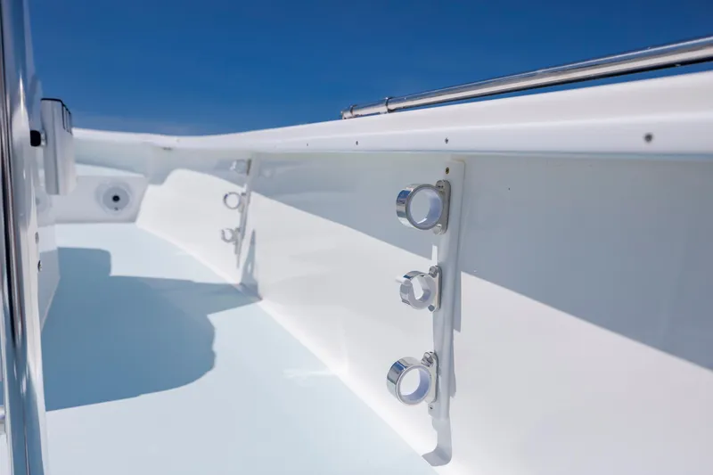 Slide: The Image of 2025 Spanish Wells 21 boat interior with rod holders, sleek white design, and clear blue sky. - 21