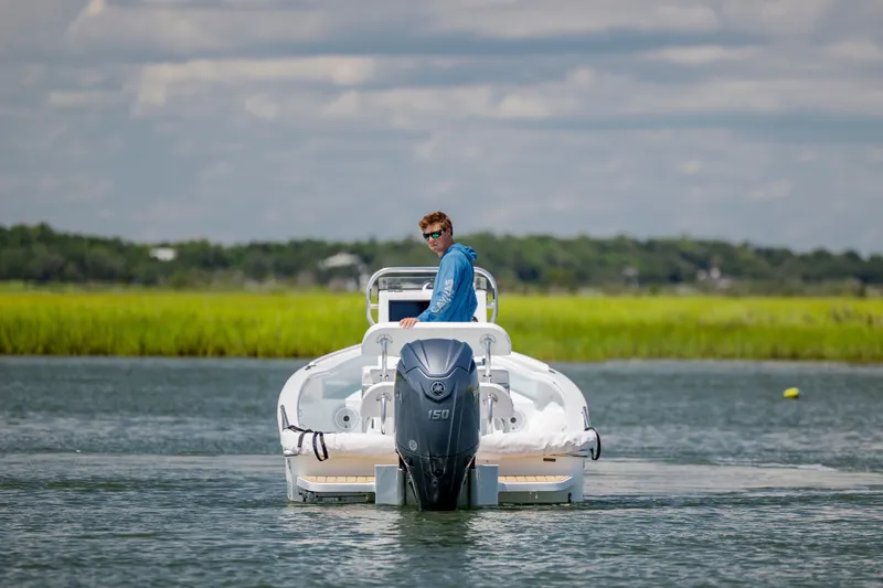 Slide: The Image of Man piloting 2025 Spanish Wells 21 boat on calm water, scenic background. - 6