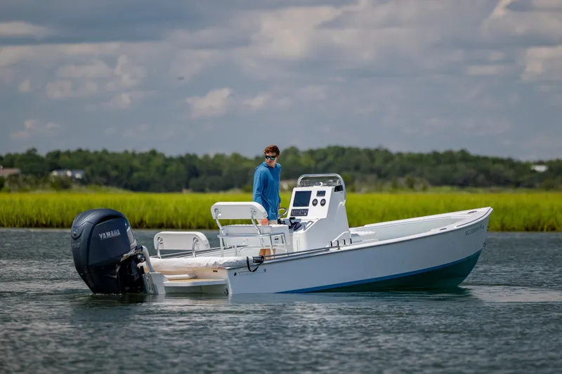 Slide: The Image of A person on a 2025 Spanish Wells 21 boat with Yamaha engine on a calm waterway. - 7