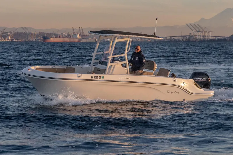 Slide: The Image of 2021 Bayliner Trophy boat cruising on open water with scenic industrial background. - 7