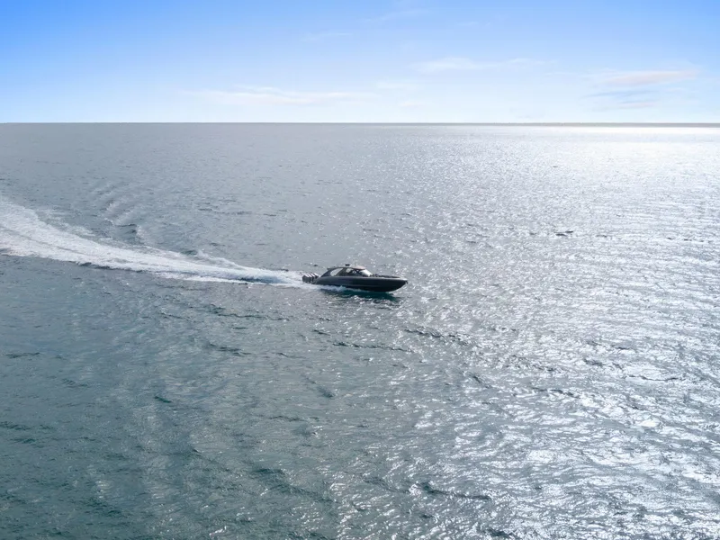 Slide: The Image of 2024 Mystic Powerboats M5200 cruising on open water under clear blue sky. - 14