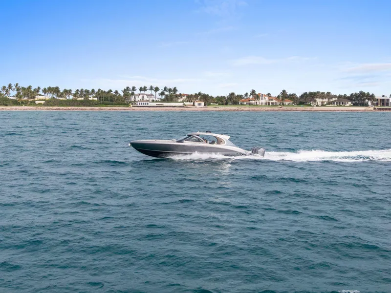 Slide: The Image of 2024 Mystic Powerboats M5200 cruising on open water near a coastal landscape. - 17