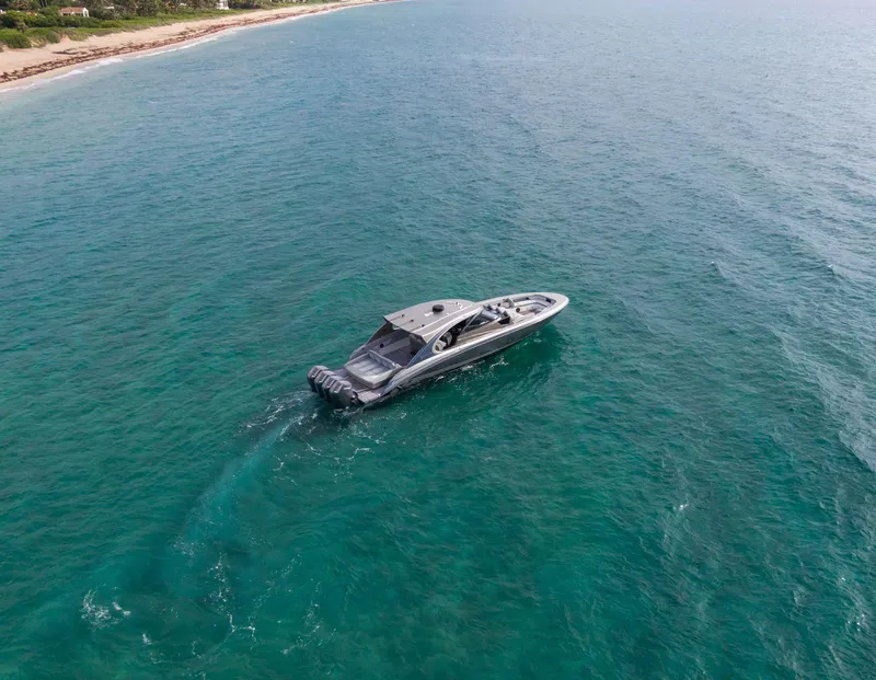 Slide: The Image of 2024 Mystic Powerboats M5200 cruising on clear blue ocean near coastline. - 6