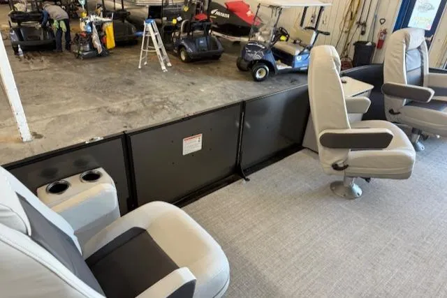 Slide: The Image of 2025 Harris Cruiser 230 interior with gray seating and cup holders in a showroom. - 10