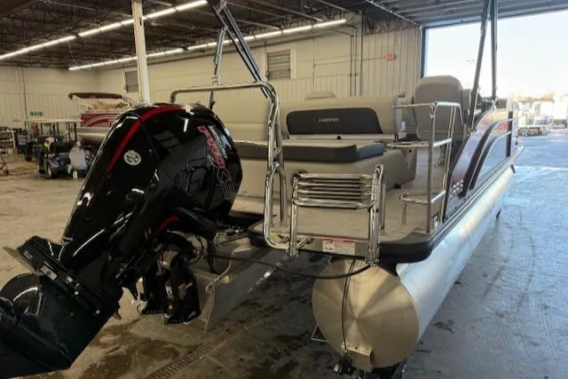 Slide: The Image of 2025 Harris Cruiser 230 pontoon boat in warehouse, featuring powerful outboard motor. - 6