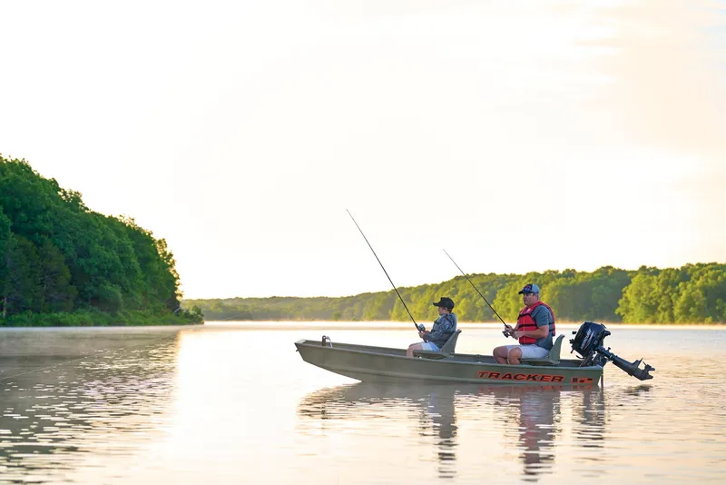 Slide: The Image of Manufacturer Provided Image: Two people fishing on a 2026 Tracker Grizzly 12 Jon boat in a serene lake. - 13