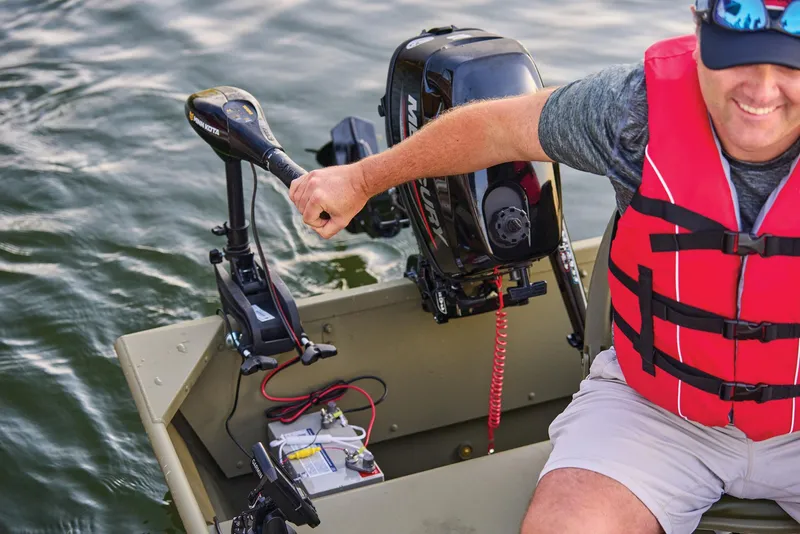 Slide: The Image of Manufacturer Provided Image: Man steering 2026 Tracker Grizzly 12 Jon boat with motor on a lake. - 19