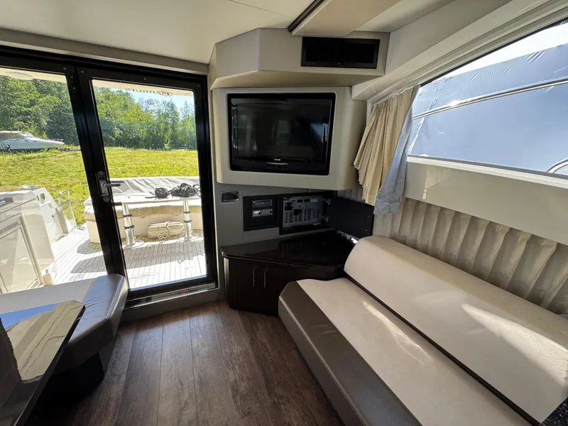 Slide: The Image of Interior of 2014 Marquis 420 Sport Bridge yacht with TV, sofa, and outdoor view. - 20