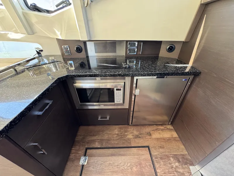 Slide: The Image of 2014 Marquis 420 Sport Bridge yacht kitchen with microwave, fridge, and sleek countertops. - 30