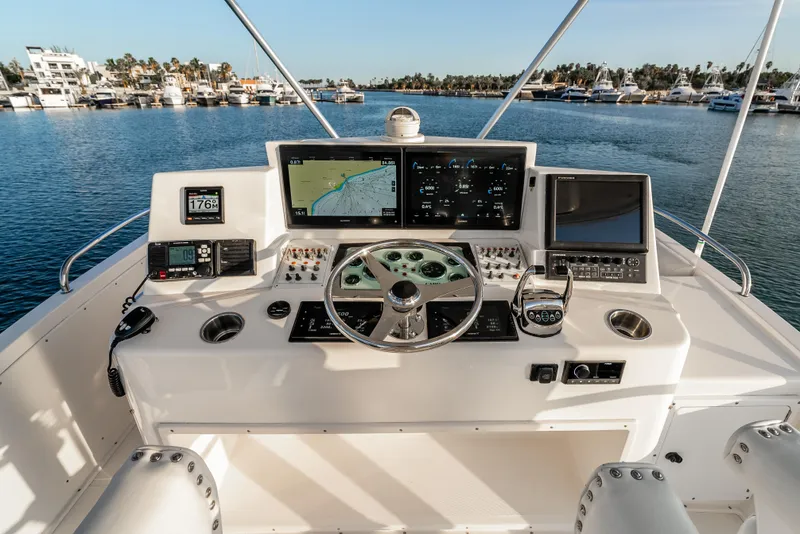 Slide: The Image of Flybridge helm of 2002 Cabo 35, featuring navigation screens and controls, overlooking marina. - 11