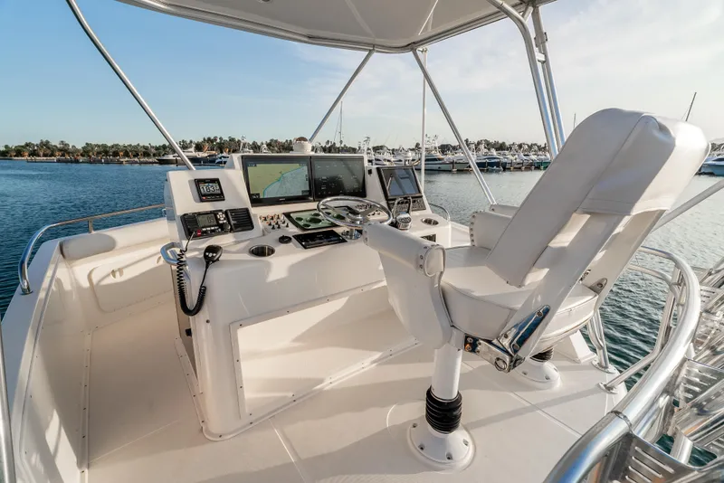 Slide: The Image of Flybridge of 2002 Cabo 35, featuring helm controls and navigation equipment, overlooking marina. - 13