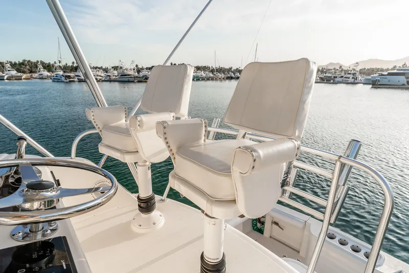 Slide: The Image of Flybridge of 2002 Cabo 35, featuring white captain chairs and marina view. - 14