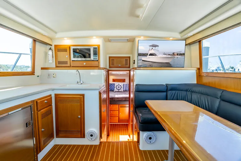 Slide: The Image of Interior of 2002 Cabo 35 Flybridge yacht with kitchen, seating, and wood accents. - 16