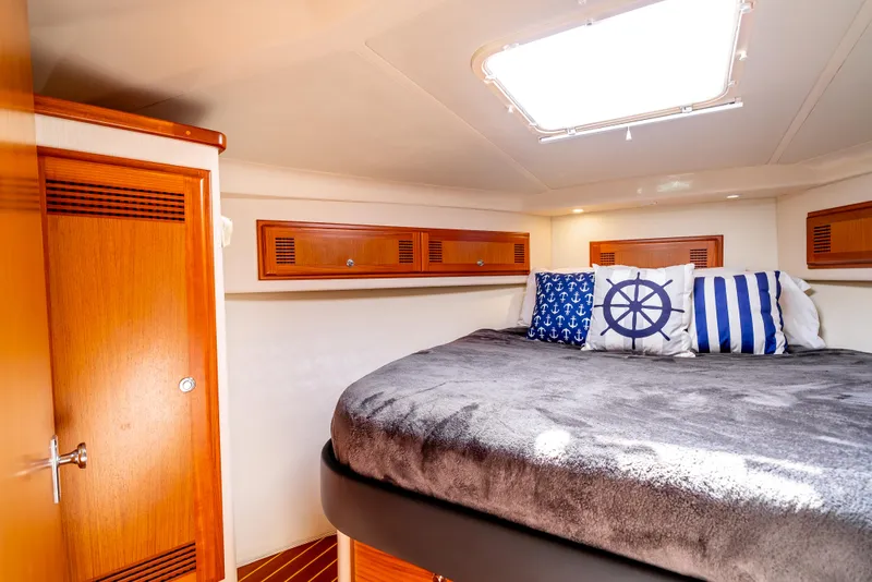 Slide: The Image of Cozy cabin interior of 2002 Cabo 35 Flybridge with nautical-themed pillows and wooden accents. - 24