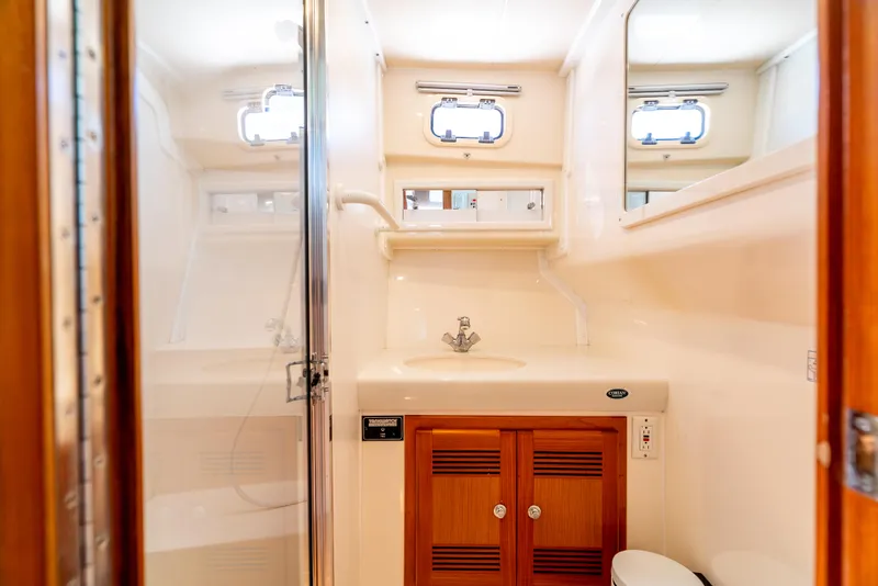 Slide: The Image of 2002 Cabo 35 Flybridge yacht bathroom with sink, mirror, and wooden cabinets. - 28