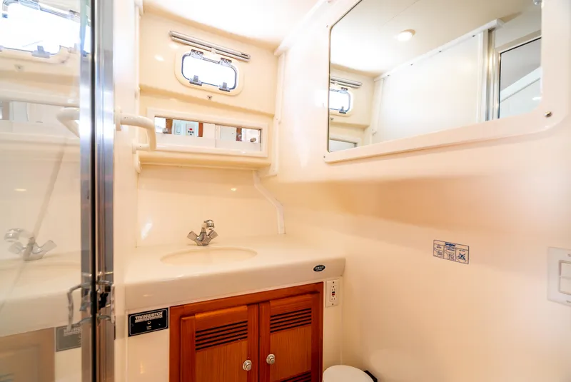 Slide: The Image of 2002 Cabo 35 Flybridge bathroom with sink, mirror, and wooden cabinet. - 29