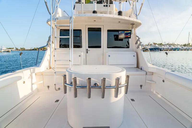 Slide: The Image of 2002 Cabo 35 Flybridge boat deck with fishing rod holders and ladder, docked by the water. - 8