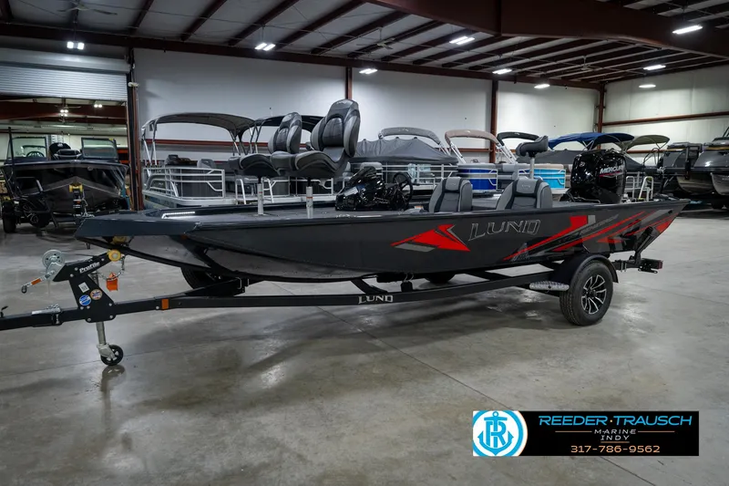Slide: The Image of 2026 Lund 1775 Renegade boat in showroom, featuring dual seats and trailer. - 2