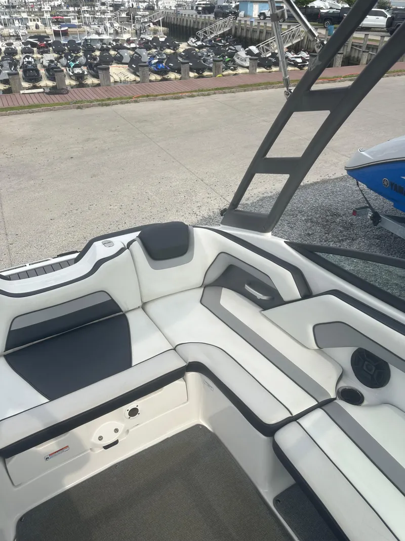 Slide: The Image of 2018 Yamaha Boats AR195 interior with sleek seating and modern design at a marina. - 13