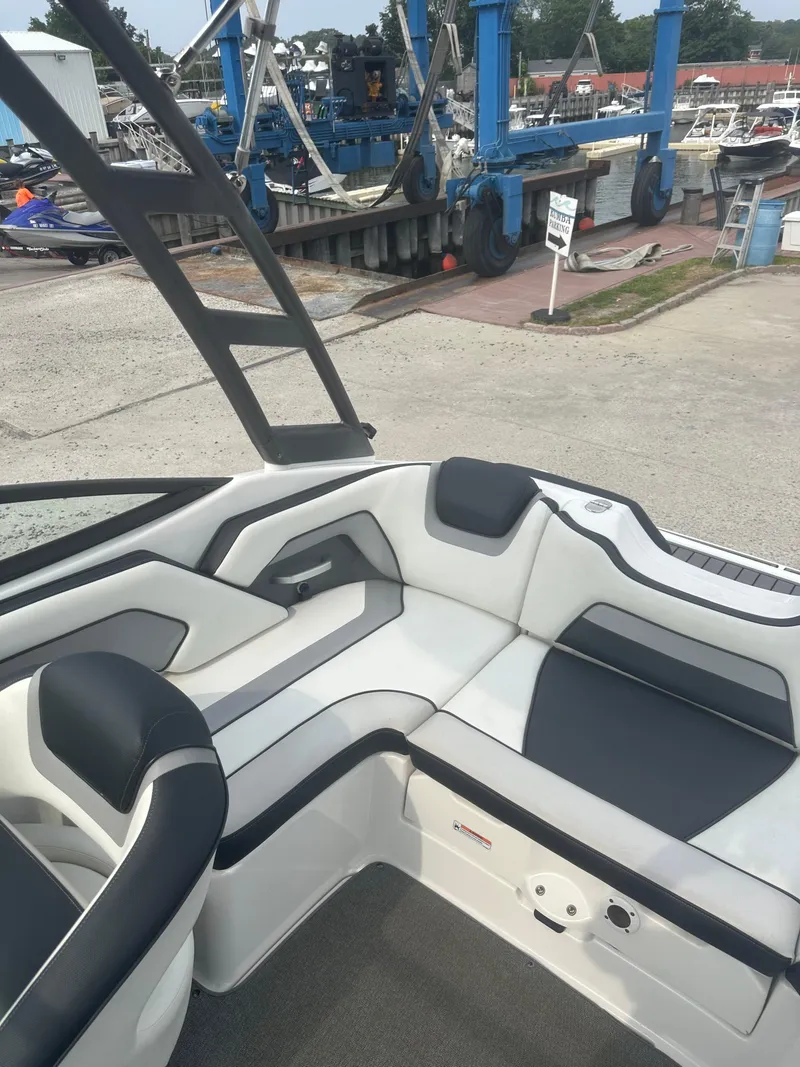 Slide: The Image of 2018 Yamaha Boats AR195 interior with sleek seating at a marina. - 14