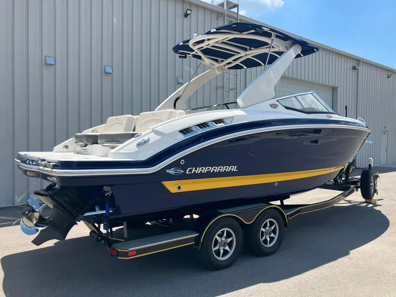 Slide: The Image of 2017 Chaparral 257 SSX boat on trailer, blue and white design, parked outside a building. - 2